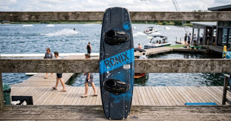 Wakeboard board avec chausses intégrées posée sur un ponton au bord d'un lac