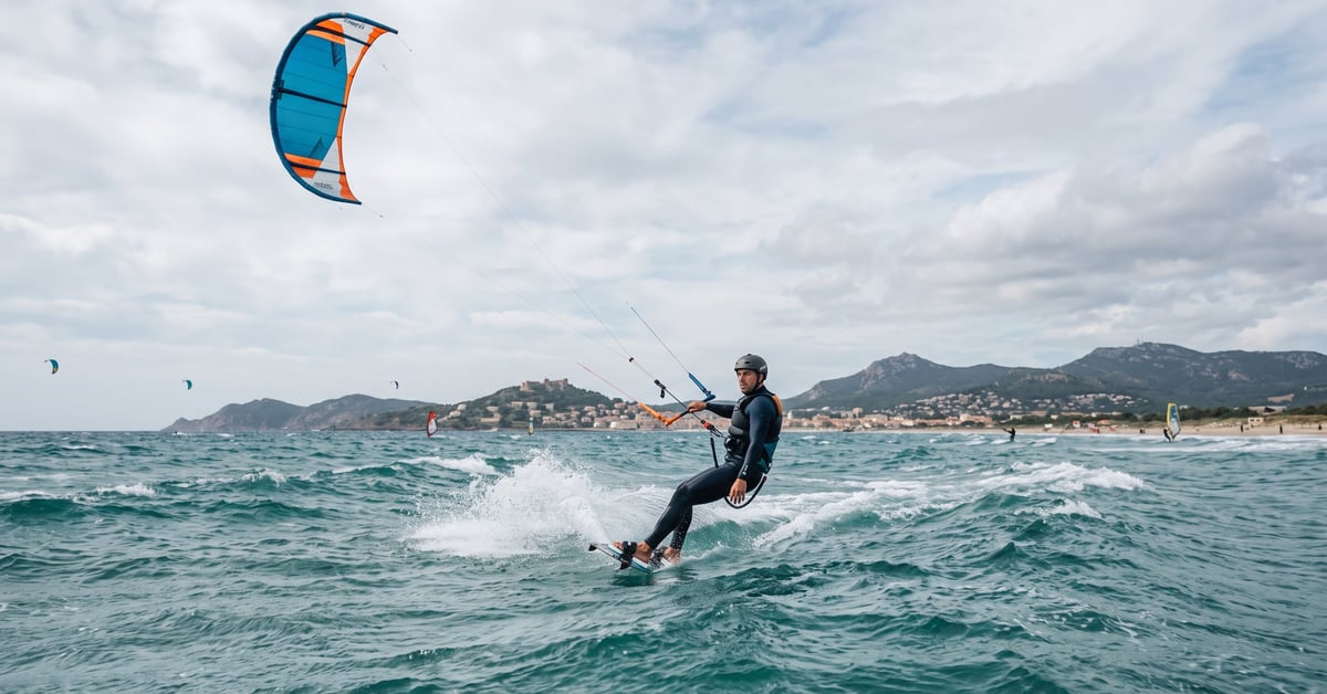 Kitesurfeur en action sur les eaux turquoise de Hyères, voile colorée déployée sous un ciel bleu
